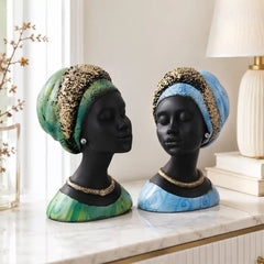 Two mannequin heads with decorative headscarves and jewelry on a marble surface.